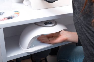 UV uçlu bir lambanın altında elini tutan bir kadın.