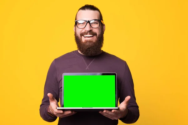 Un homme barbu sourit à la caméra portant une paire de lunettes tient un ordinateur — Photo