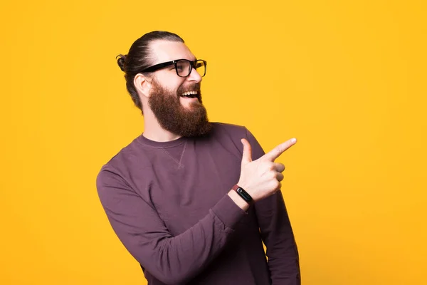 Fénykép egy fiatal szakállas férfi visel galsses elmutat, és mosolyog — Stock Fotó