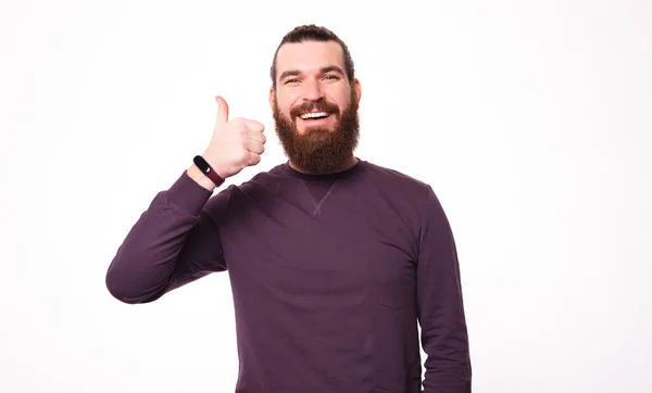 Картина бородатого молодого чоловіка посміхається в камеру і показує великий палець вгору — стокове фото