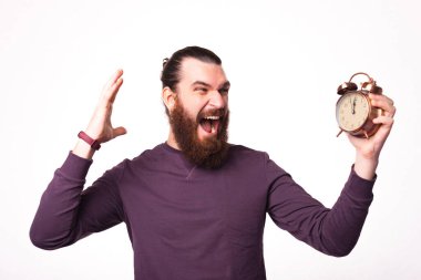 Heyecanlı sakallı bir adam saatine bakıyor.