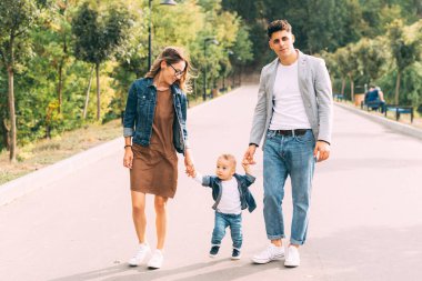 Park 'ta mutlu mesut yürüyen bir ailenin fotoğrafı.