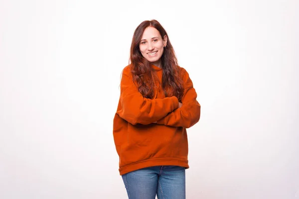 Mujer joven de pie con los brazos cruzados y sonriendo a la cámara — Foto de Stock