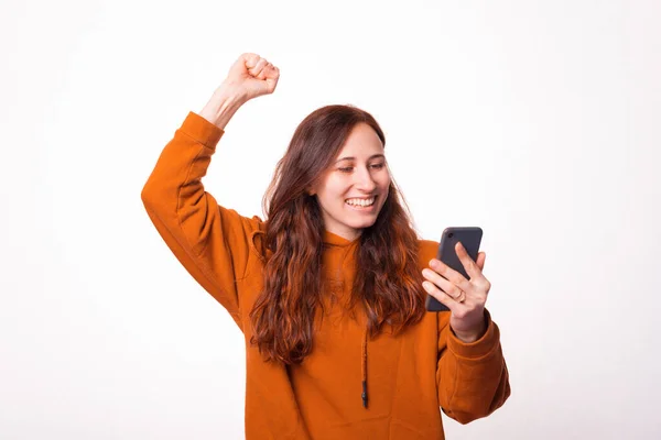 Egy nő, aki a telefonját nézi, izgatott, mert nyert. — Stock Fotó