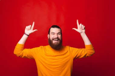 Neşeli sakallı adam heyecanlı bir şekilde kameraya bakıyor.