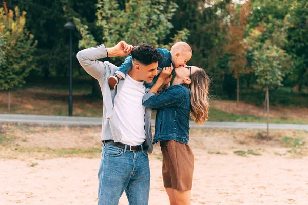 En familj i parken och hustrun kysser barnet — Stockfoto