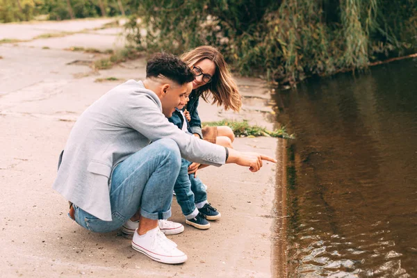 A nice photo of a family near a lake pointing at it — Stock Photo, Image