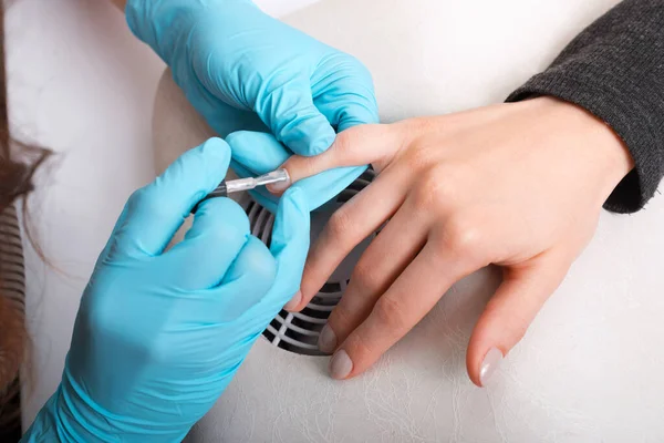 Um mestre de unhas está pintando unhas de mulher com cinza — Fotografia de Stock