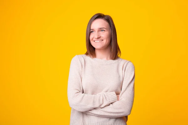 Portret van een lachende jonge vrouw met gekruiste armen die wegkijkt — Stockfoto