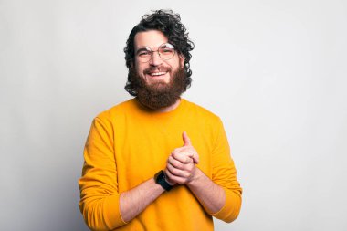 Gözlüklü genç bir adam kameraya bakarken gülümsüyor.