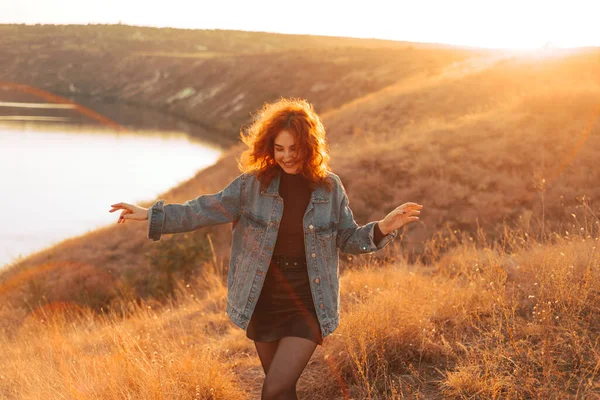 A nice young woman is walking on a colline smiling on a sunny day