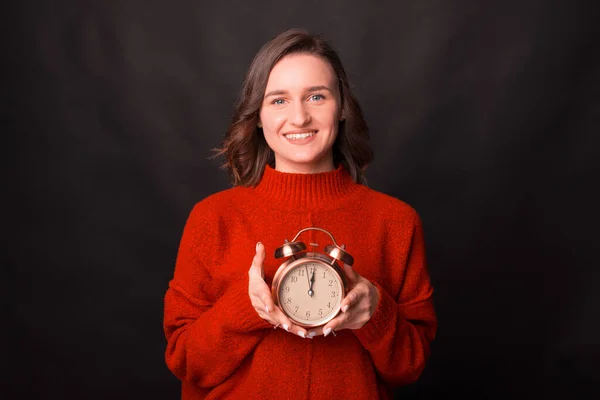 Jovencita alegre sonríe a la cámara y sostiene un reloj — Foto de Stock