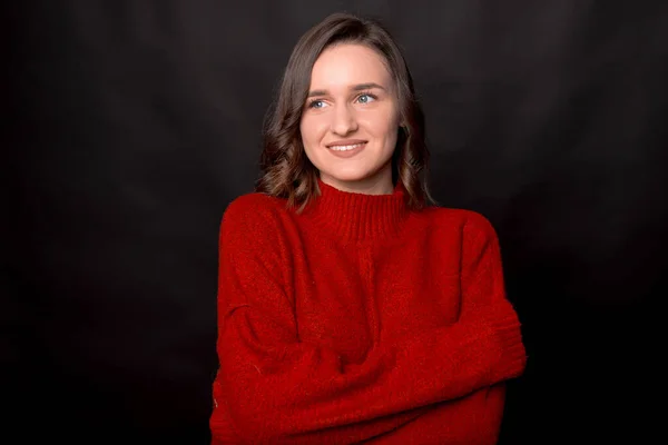Sonriente joven morena chica en suéter rojo posando aislado sobre fondo oscuro estudio retrato — Foto de Stock
