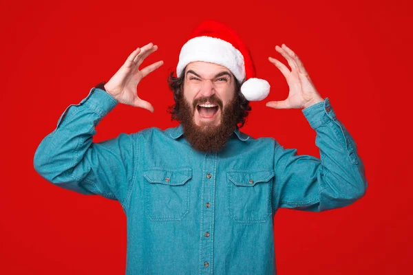 Az észbontó gesztust egy fiatal szakállas férfi teszi, aki karácsonyi kalapot visel.. — Stock Fotó