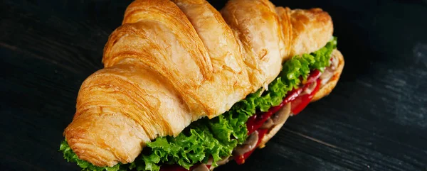 Delicious croissant with fresh vegetables and lettuce on black table — Stock Photo, Image