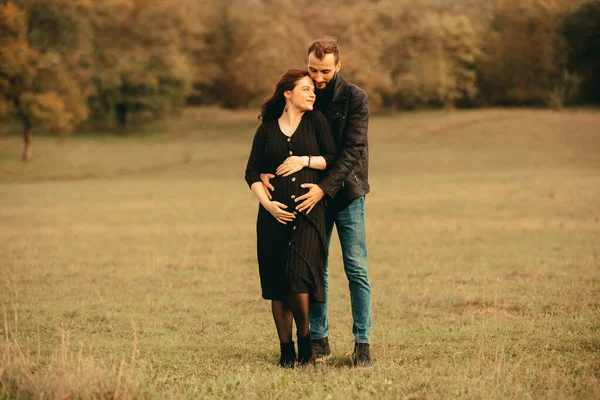 Photo de couple heureux futurs parents sur la promenade dans le parc, étreignant par derrière — Photo