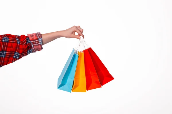 Primer plano de la mano famale sosteniendo pequeñas bolsas de compras de colores sobre un fondo blanco aislado —  Fotos de Stock