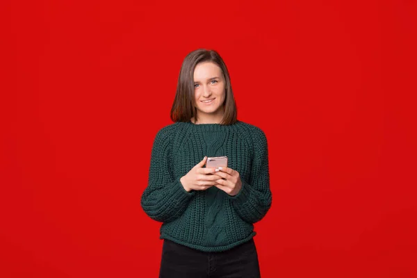 Retrato de uma jovem feliz usando telefone celular isolado sobre fundo vermelho — Fotografia de Stock