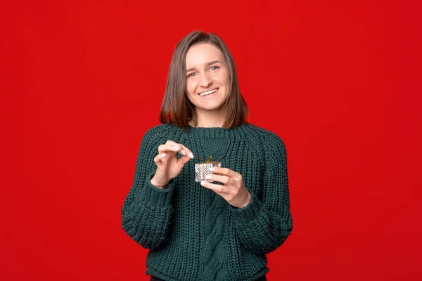 Feliz sorrindo jovem segurando pequena caixa de presente sobre vermelho isolado estúdio fundo — Fotografia de Stock