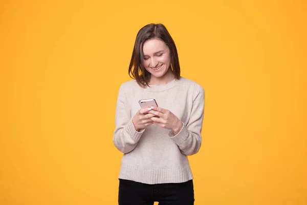 Menina feliz está enviando mensagens para alguém e sorrindo — Fotografia de Stock