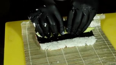 Suşi ustasının avokado ve balıktan rulo yaptığı görüntüleri kapat.