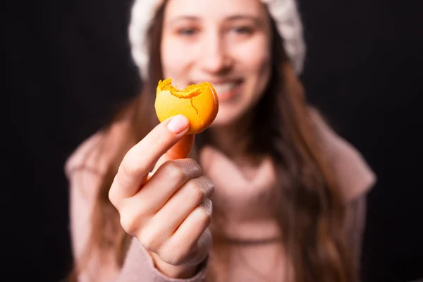 Macaroon kuning digigit dipegang oleh seorang gadis cantik tersenyum. — Stok Foto