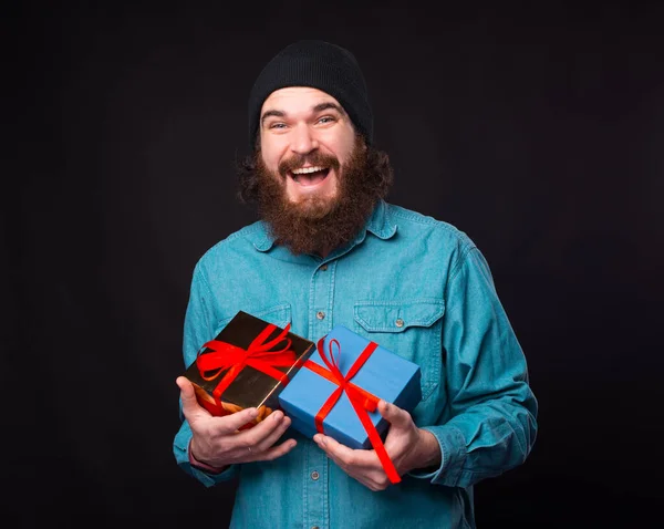 Ενθουσιασμένος hipster μπλε πουκάμισο κρατά κάποια κουτιά δώρων. — Φωτογραφία Αρχείου
