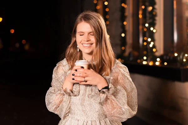 Young lady wishes for something while she is holding a take away cup outdoors. — Stock Photo, Image