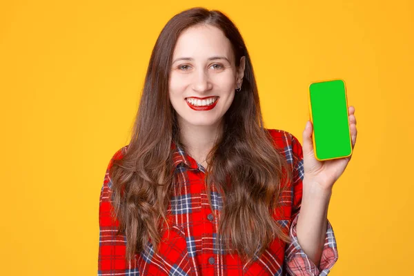 Mulher alegre em camisa quadriculada vermelha sorrindo e mostrando smartphone com tela verde — Fotografia de Stock