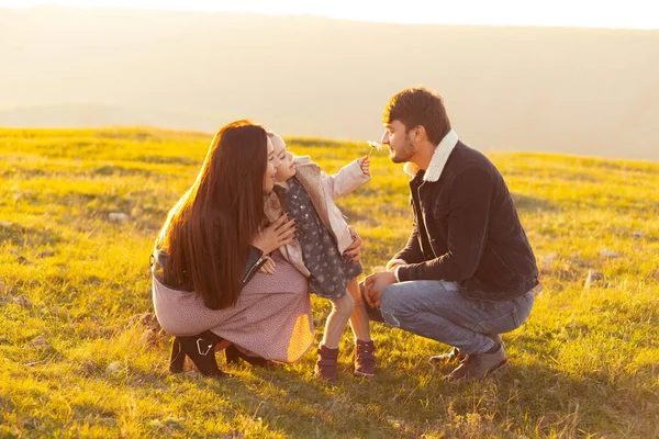 Foto de família de pais felizes tendo tempo com a filha na natureza no pôr do sol — Fotografia de Stock