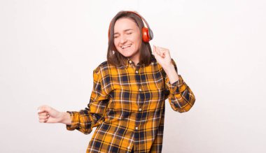 Heyecanlı genç kadın kulaklıkla müzik dinlerken dans ediyor..