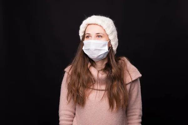 Ritratto di una giovane ragazza con una maschera medica isolata su uno sfondo nero. — Foto Stock
