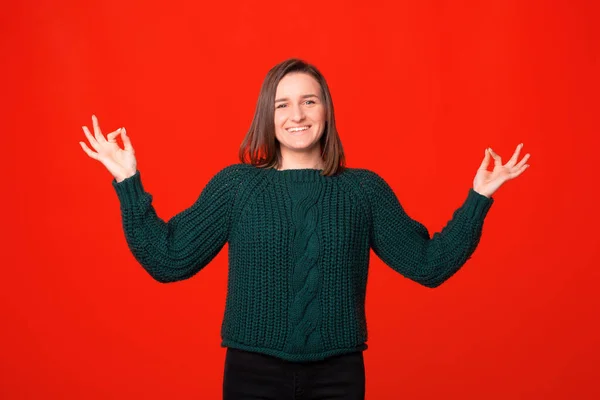 Veselá mladá dáma se drží za ruce pro meditaci nad červeným pozadím — Stock fotografie