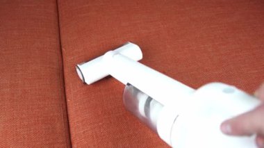 Elektrikli süpürgenin çalıştığı, turuncu kanepeyi temizlediği görüntüleri kapat.