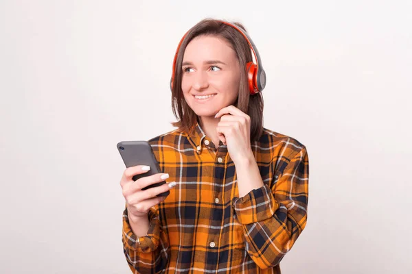 Giovane ragazza felice sta ascoltando la musica attraverso le cuffie e tenendo il telefono. — Foto Stock