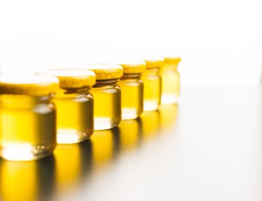 Beyaz bir masa ve arka planda küçük bal ıhlamur kavanozlarından bir sıra.