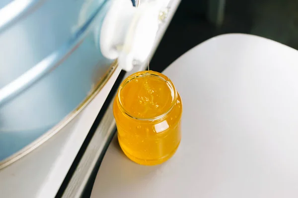 Fotografie sklenice poblíž nádržky z medu ve výrobní sekci — Stock fotografie
