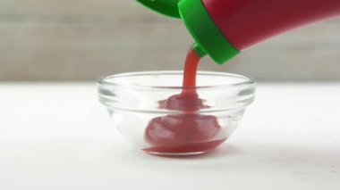 Şeffaf küçük bir kaseye ketçap dökerken çekilmiş görüntüleri kapat.