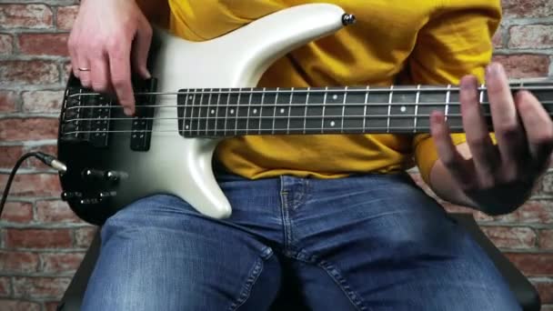 Close-up beelden van man spelen op bas gitaar in zijn studio — Stockvideo