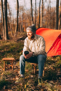 Mutlu gezgin çadırın yanındaki taburede oturuyor.