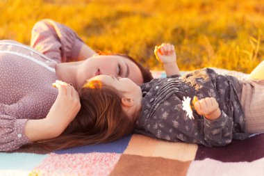 Anne ve kızı tarlada battaniyede yatıyor.