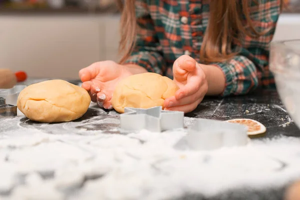 Little girl is preparing dough for gingerbread biscuits.