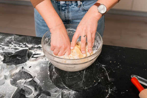 As mãos femininas estão amassando alguma massa em uma mesa preta. — Fotografia de Stock