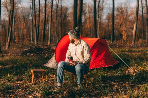 Bearded man with takeaway cup resting near tent — Stock Photo, Image