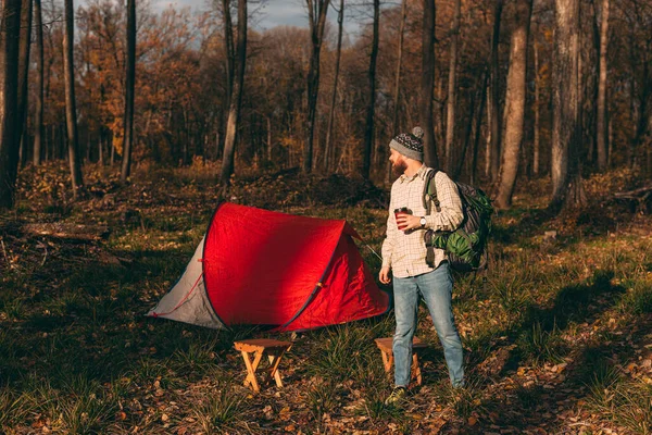 Male traveler with drink to go and backpack on campsite — Stock Photo, Image