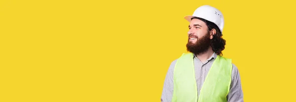 Portret uśmiechniętego inżyniera lub architekta noszącego kamizelkę i kask i odwracającego wzrok — Zdjęcie stockowe