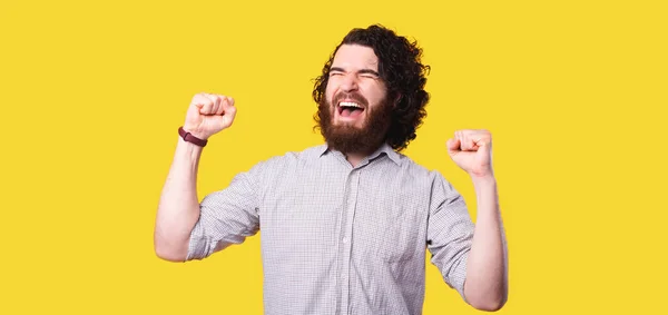 Man met baard viert overwinning met vuisten omhoog en schreeuwen over gele achtergrond — Stockfoto