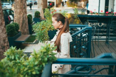 Hoş bir genç bayan gün ışığında şehrin dışındaki bir kafeden dışarı çıkıyor.
