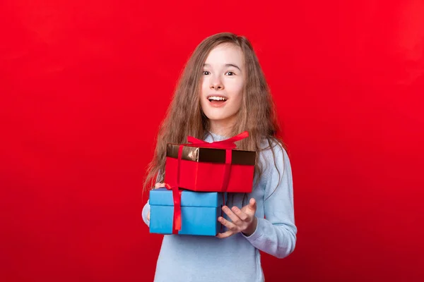Porträt eines überraschten kleinen Mädchens mit Geschenkschachteln auf rotem Hintergrund — Stockfoto