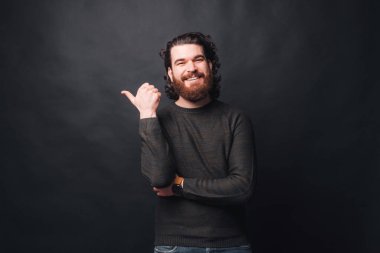 Siyah arka planda kıvırcık saçlı neşeli sakallı adamın fotoğrafı.